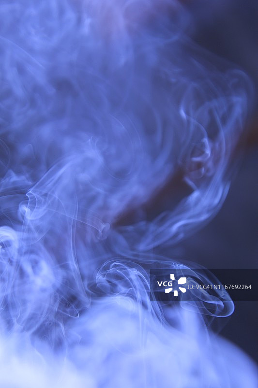 香棍缭绕，烟从香中燃烧。美丽的烟雾。蓝色创意抽象特写背景。模糊的背景和设计与复制空间图片素材