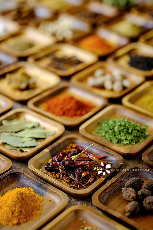 各种彩色的，有机的，干燥的，充满活力的印度食物香料在一个古老的木材背景木托盘。图片素材