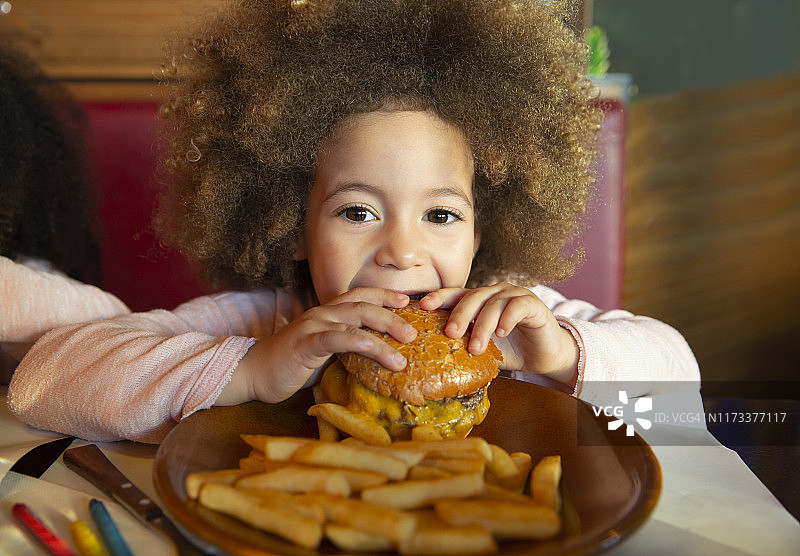 民族小女孩在吃汉堡和薯条图片素材