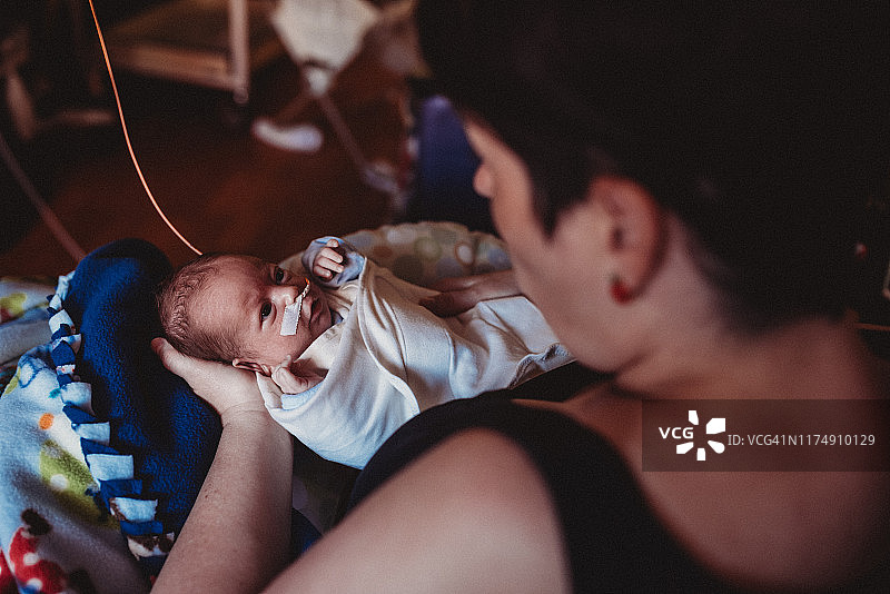 29周早产儿握着母亲的手，在新生儿重症监护室被抱着图片素材