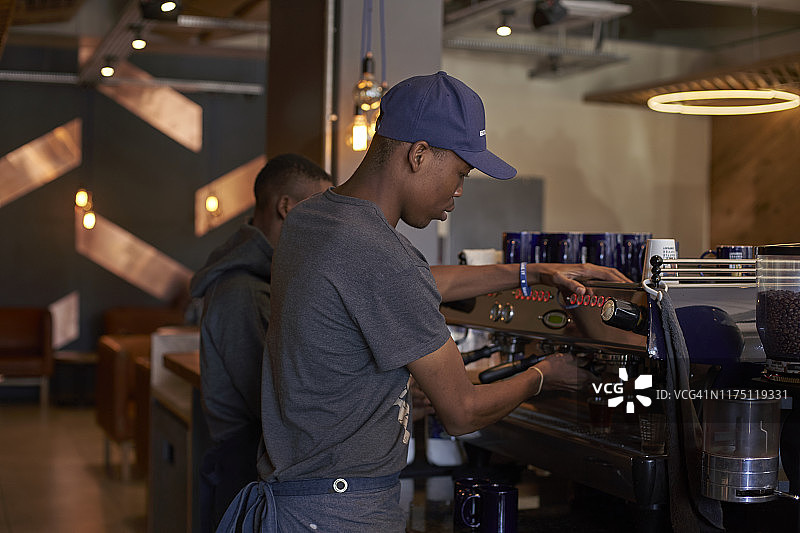 一个年轻人正在咖啡店里煮咖啡图片素材