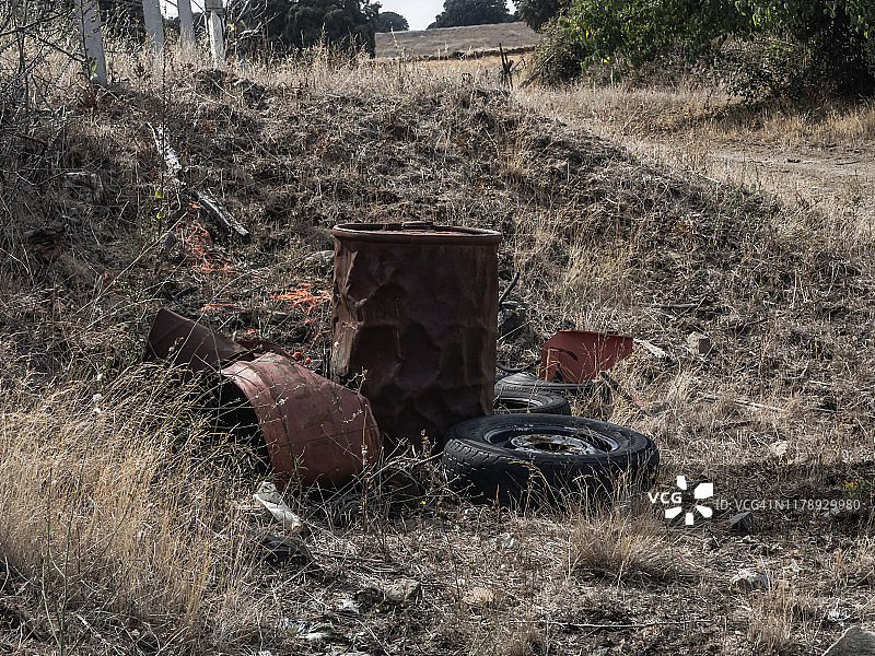 生锈的金属鼓被扔在野外，遗弃了。农村人口减少的概念图片素材