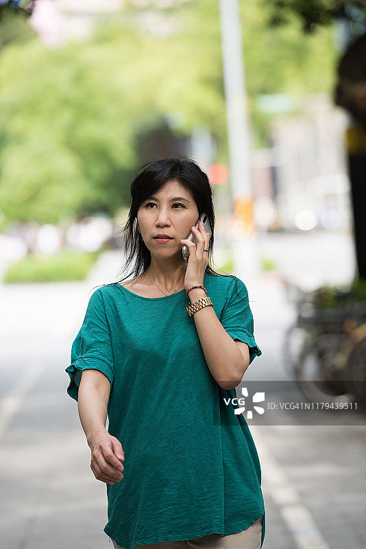 一名拿着手机的女子走在台北大街上图片素材