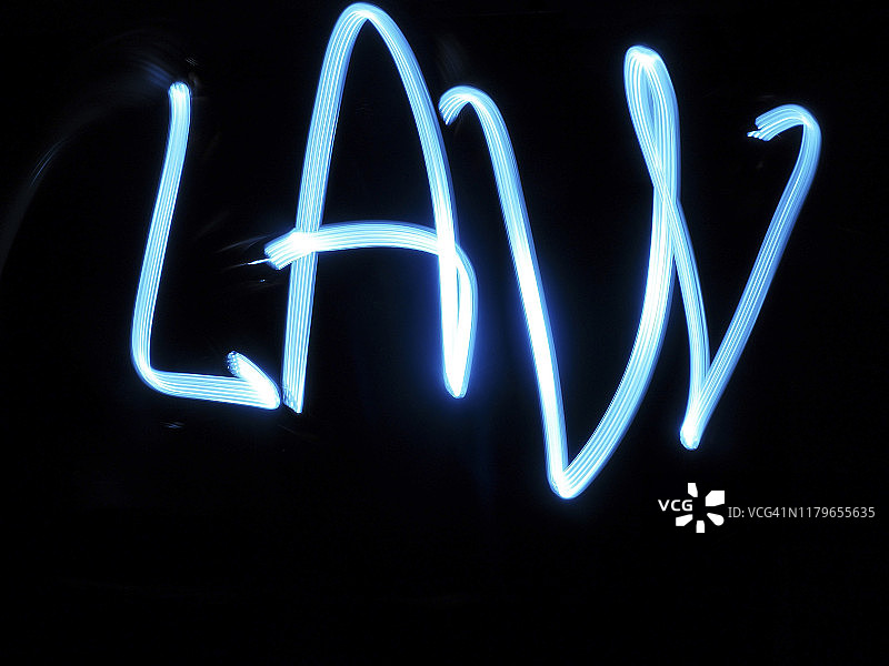 用明亮的光线在黑色背景下书写的法律。图片素材
