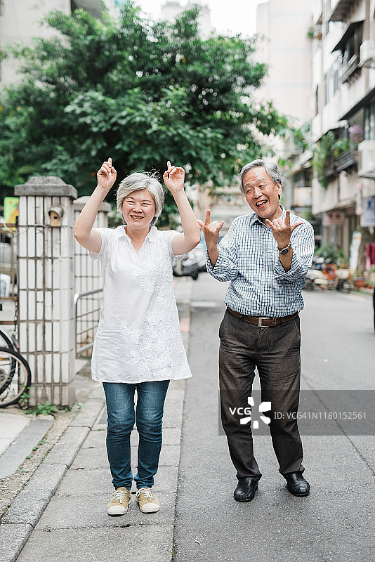 微笑着，深情的老年夫妇走在城市的人行道上图片素材