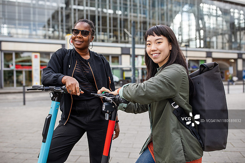 微笑的女性朋友推着摩托车在城市里图片素材