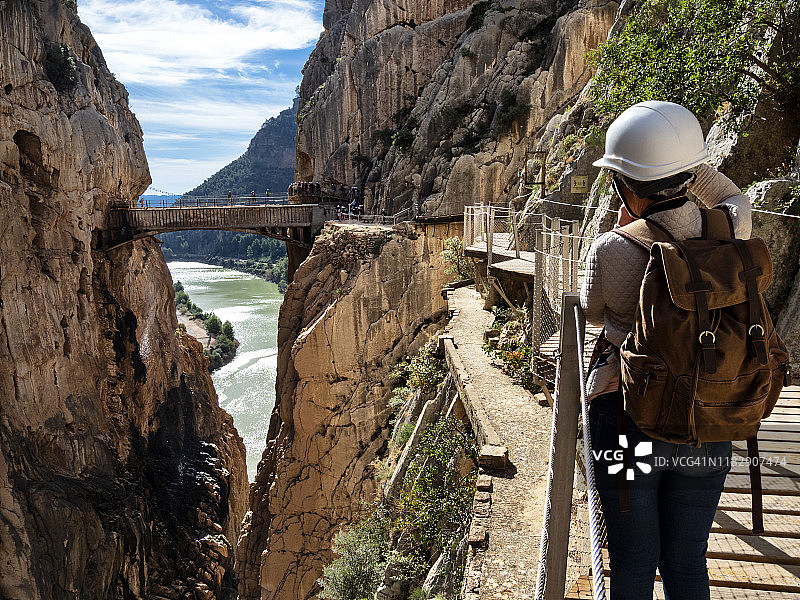 徒步旅行者在大自然中行走在一座木桥上，钉在峡谷的岩壁上达到很高的高度。卡米尼托·德尔雷(《国王大道》)。图片素材