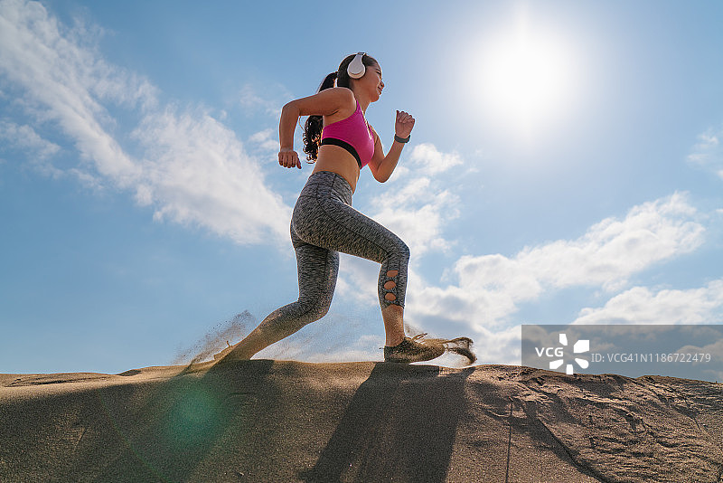 年轻健康的女运动员在海滩上跑步图片素材