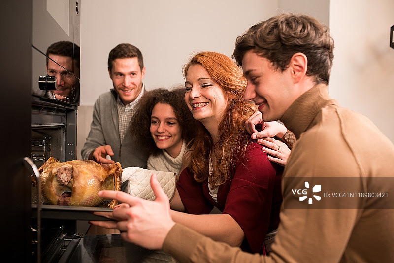 参加烤制感恩节火鸡的家庭成员图片素材