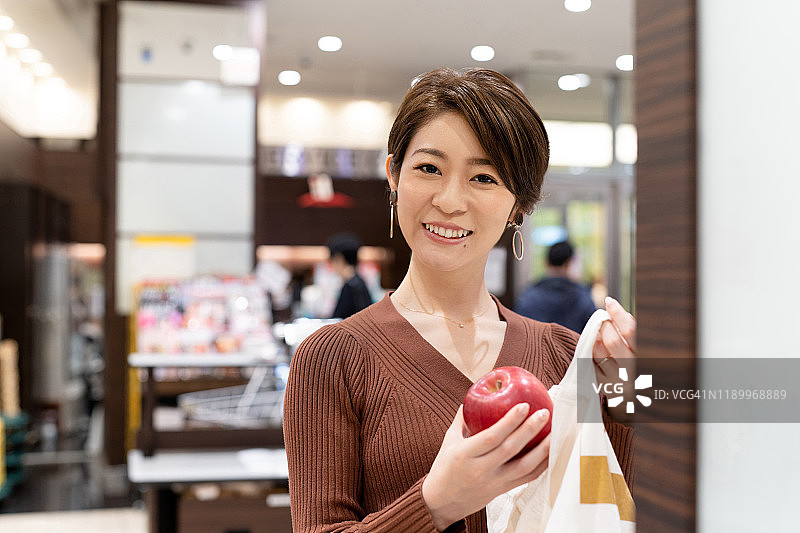 亚洲妇女在超市用可重复使用的棉花袋包装苹果图片素材
