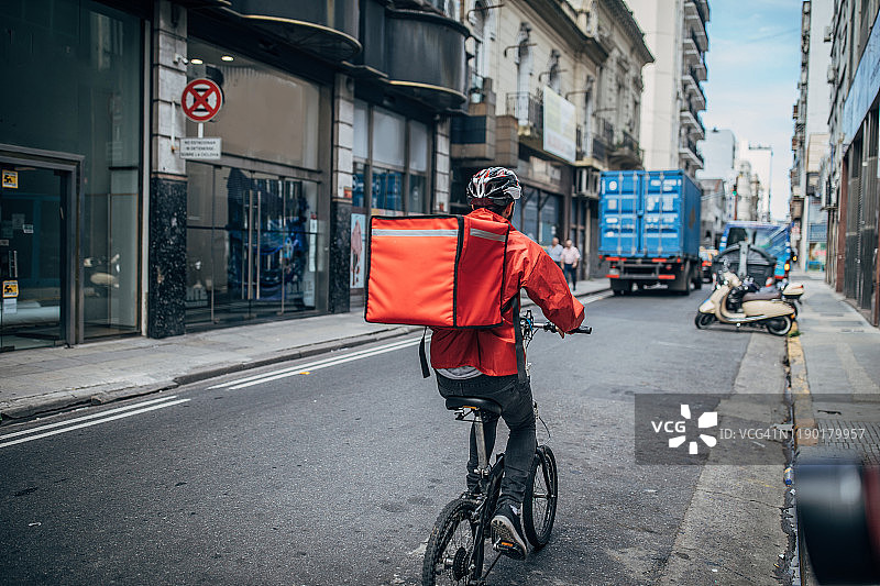 在城市里骑自行车的快递员图片素材