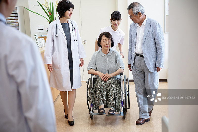 医生和男人走，而女护士推着坐在轮椅上的老妇人图片素材