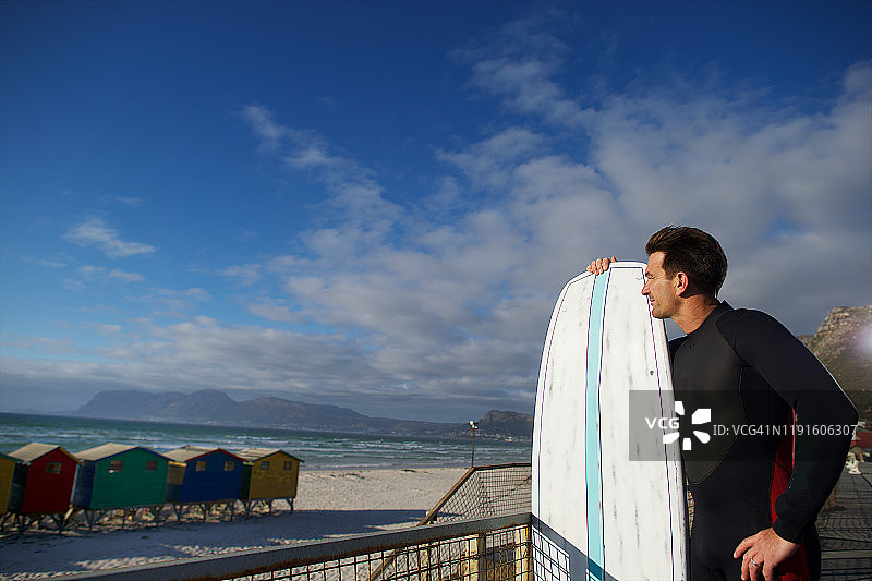 冲浪者和他的冲浪板俯瞰着五颜六色的海滩小屋图片素材