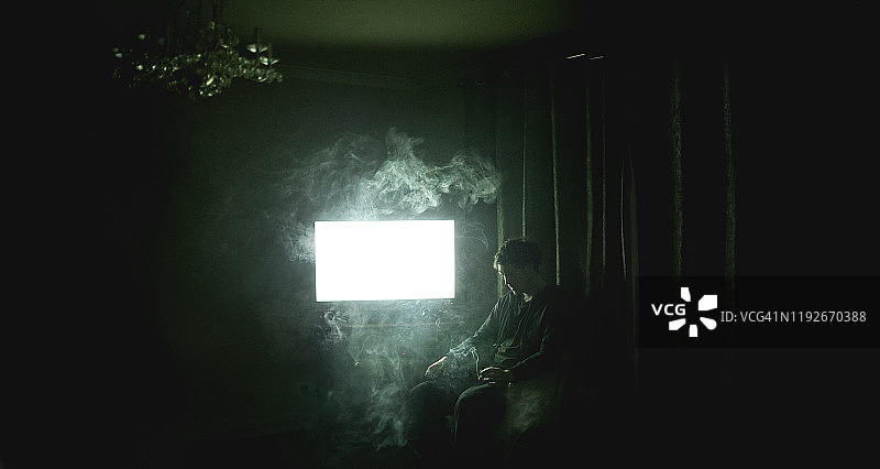 坐在黑屋子里抽烟的男人图片素材