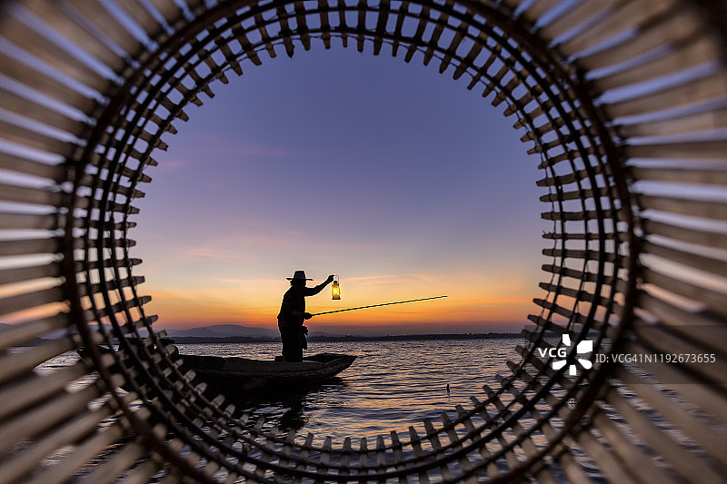 剪影渔民鱼竿与钩在船上。概念渔民的生活方式泰国文化。图片素材