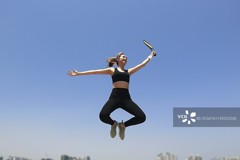 年轻女子用网球拍跳起来图片素材