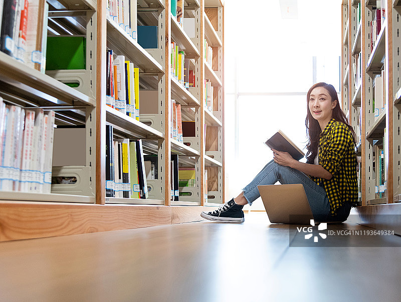 一个女人坐在图书馆的地板上看书图片素材