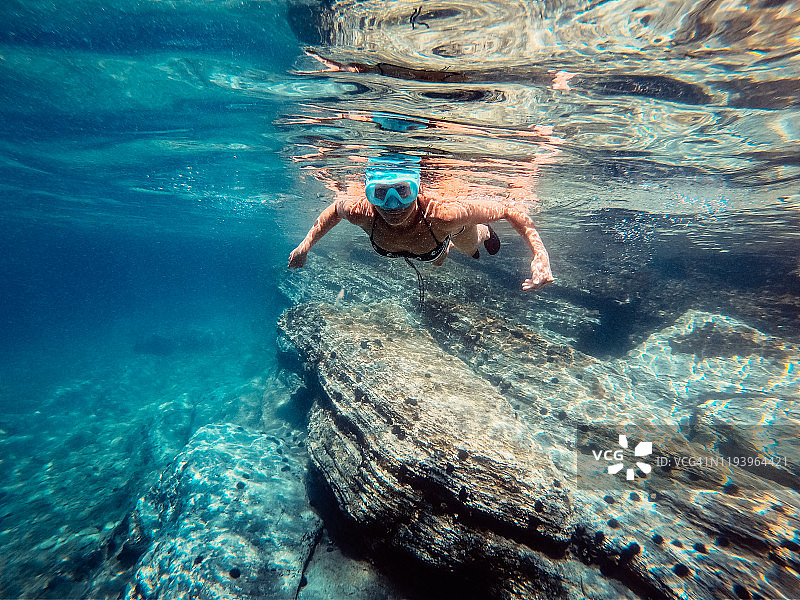 女人浮潜在珊瑚礁附近的海里图片素材