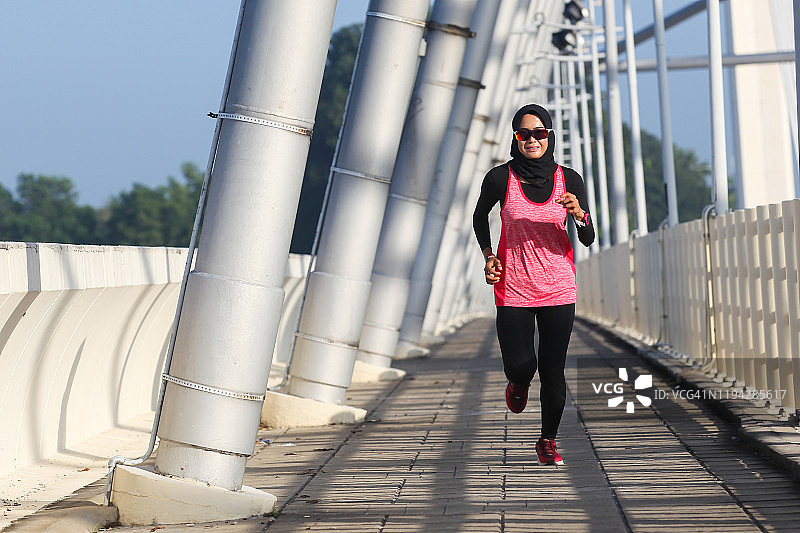 女子铁人三项运动员在桥上跑步图片素材