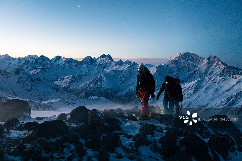 登山运动员在日出时登上积雪的山脊图片素材