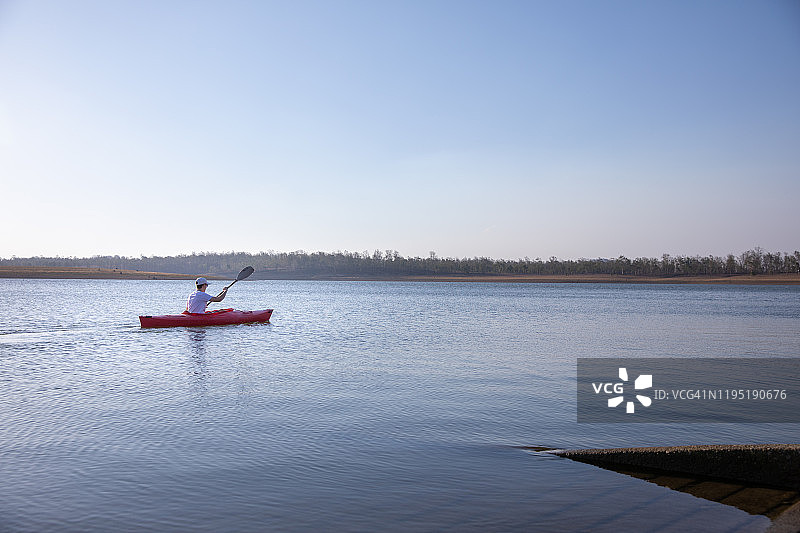 一个十几岁的男孩在湖上划着皮划艇图片素材