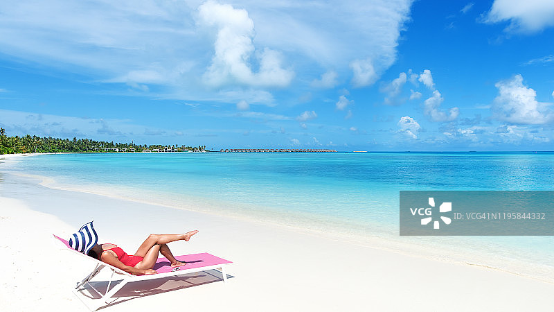 年轻迷人的女人在马尔代夫海滩日光浴-夏季海滩度假概念图片素材