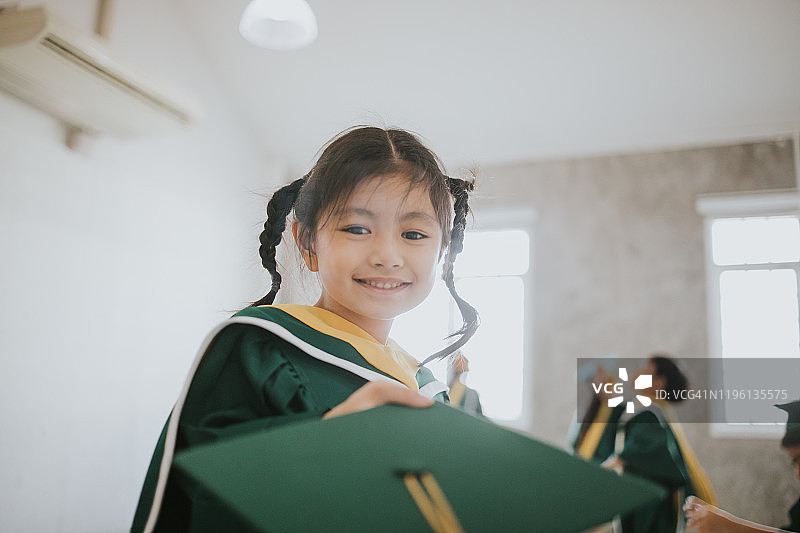 泰国可爱的宝贝女孩收到她的毕业帽与毕业日股票照片图片素材