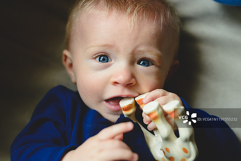 一个小男孩在咀嚼玩具。图片素材