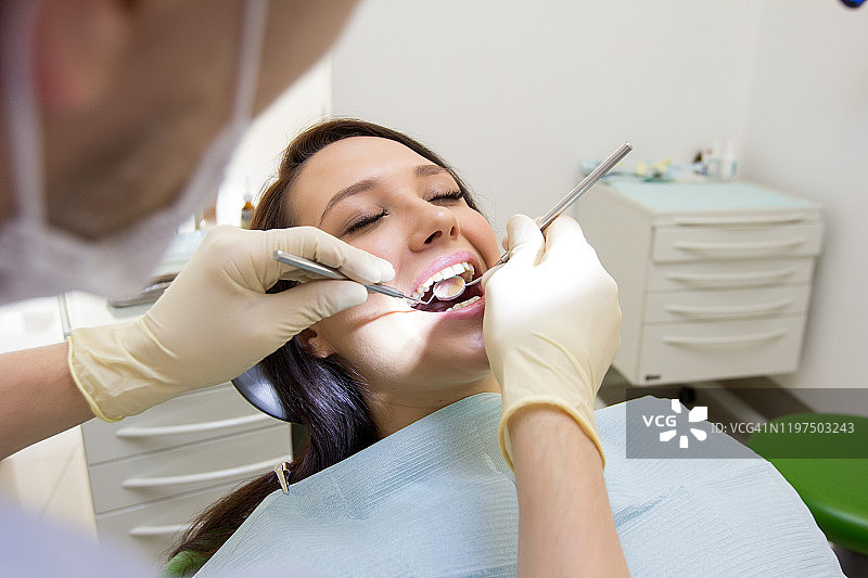 牙医检查病人的牙齿。雪白的微笑，牙科工具图片素材
