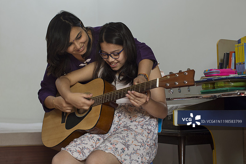 母亲帮助女儿弹吉他图片素材