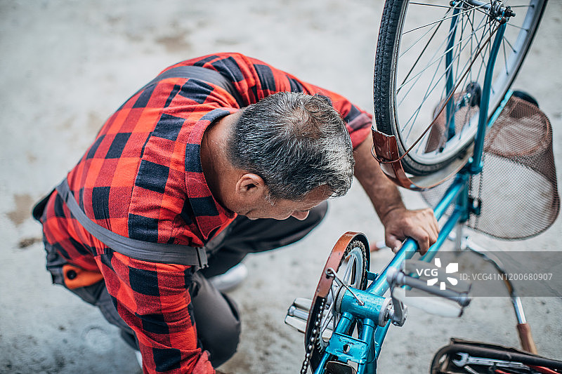 一个成熟的男人独自修自行车图片素材