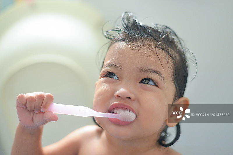 口腔卫生。亚洲可爱的女孩或小孩在浴室里用牙刷刷牙。医疗保健的概念。图片素材
