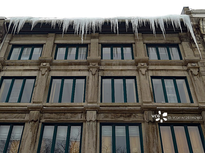 在蒙特利尔，冰钟乳石从积雪的屋顶上落下图片素材