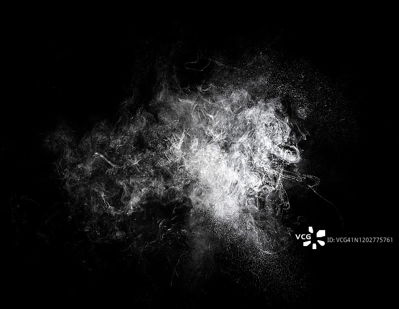 由一团白色粉末颗粒在黑色背景上撞击而成的爆炸。图片素材