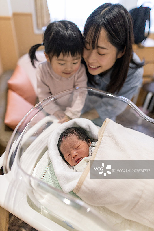 母亲和小女儿在医院看着刚出生的婴儿图片素材