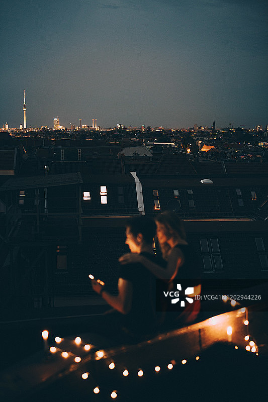 一对夫妇坐在黄昏的城市景观的照明露台上的高角度视图图片素材