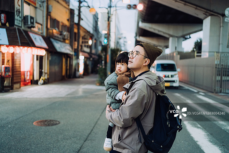 年轻的亚洲父亲带着他可爱的小女儿在城市街道上散步和探索图片素材
