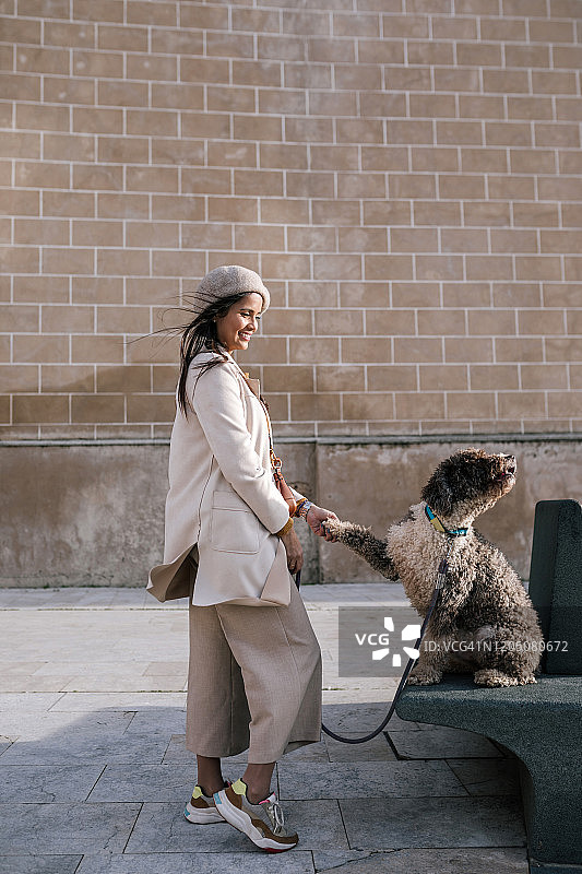 一个年轻女人和她的狗在城市里给爪子图片素材
