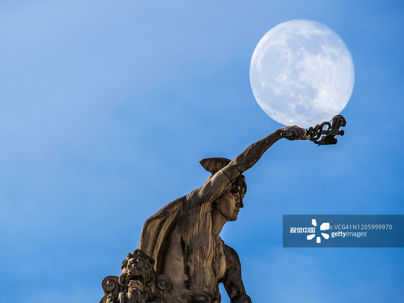 低角度的雕像对蓝天与月亮图片素材