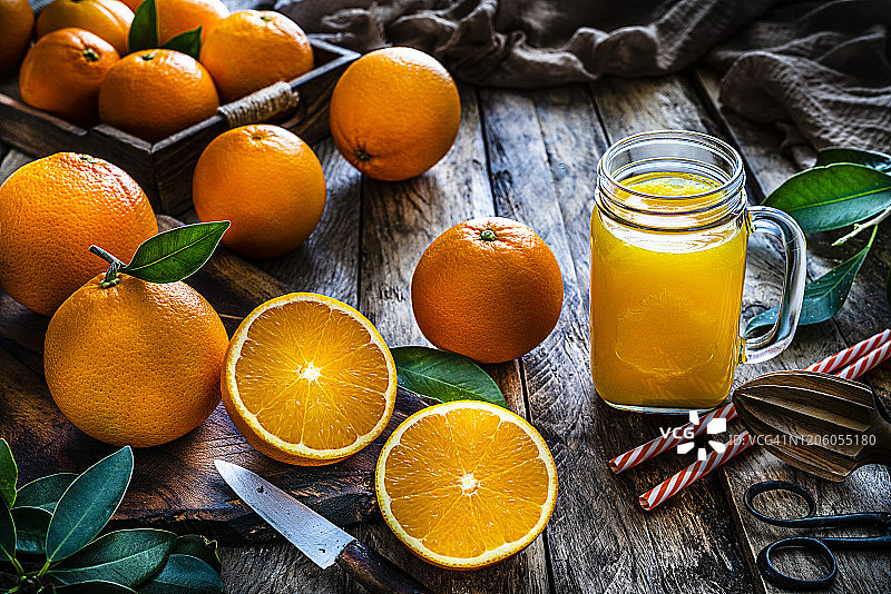 自制的橙汁装在梅森瓶里，放在质朴的木桌上图片素材