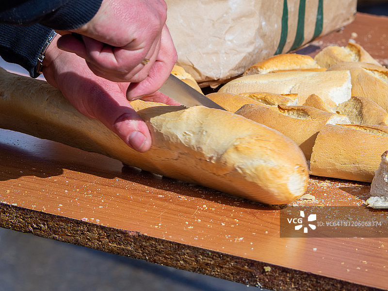 佩拉布拉沃的马塔扎传统节日。在木桌上用刀切面包的人图片素材