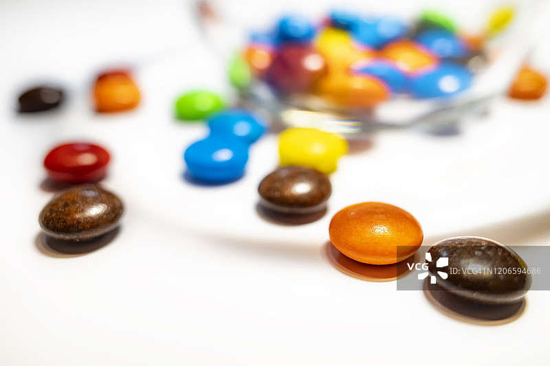 玻璃碗和彩色的巧克力豆在白色的背景图片素材