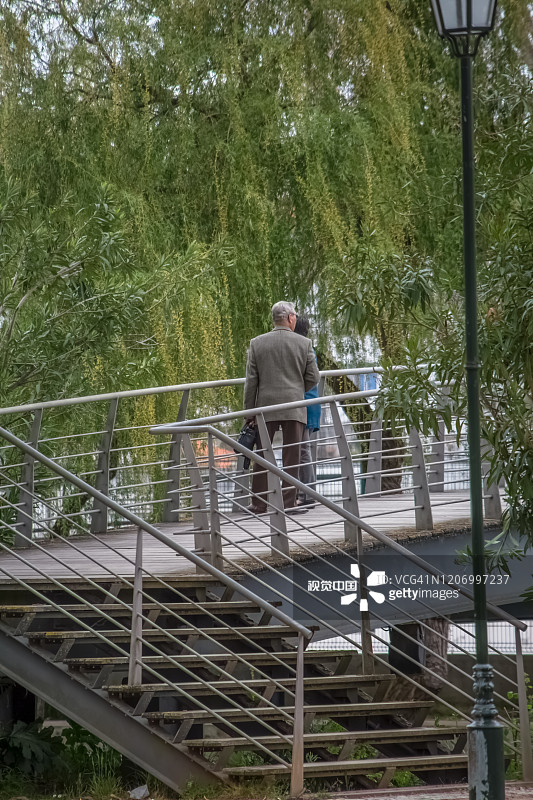 托马尔市中心，一对老年夫妇在一座现代金属桥上的景色图片素材