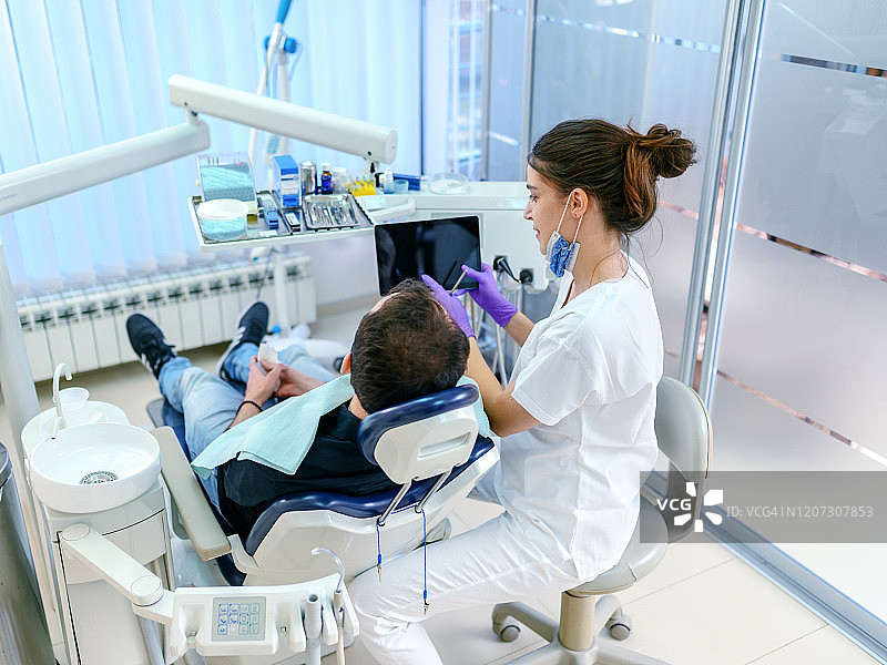 微笑的牙医和病人看数字平板在诊所图片素材
