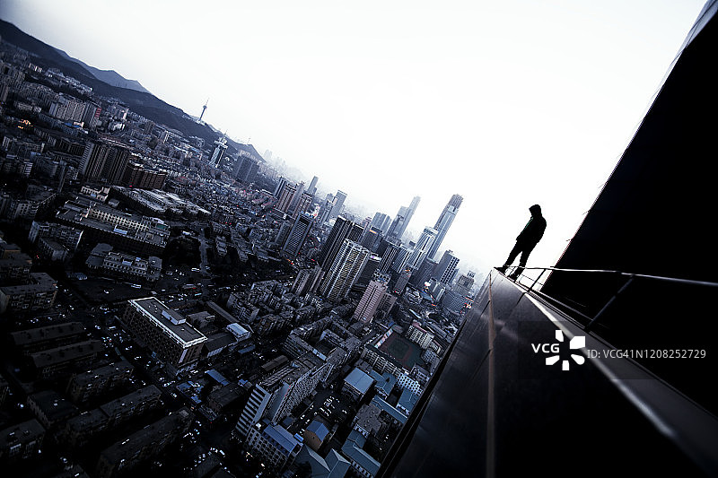 一个年轻人站在屋顶上俯瞰城市图片素材