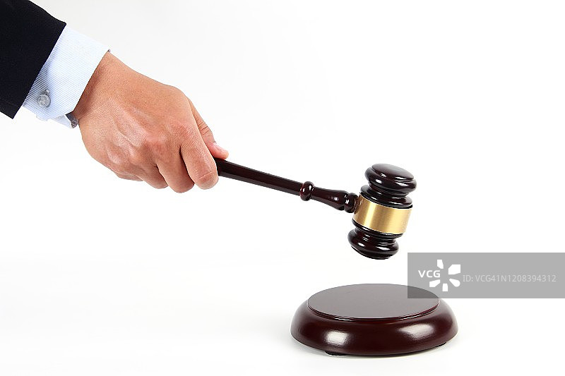 男子手里握着一个木制的法官木槌，孤立在白色的背景下，法律和拍卖概念图片素材