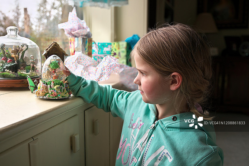 一个小女孩欣赏她刚刚打开的复活节主题的雪球图片素材