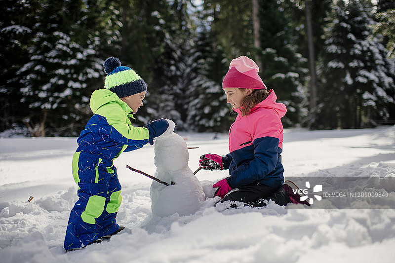 哥哥和姐姐在冬天堆雪人的照片图片素材