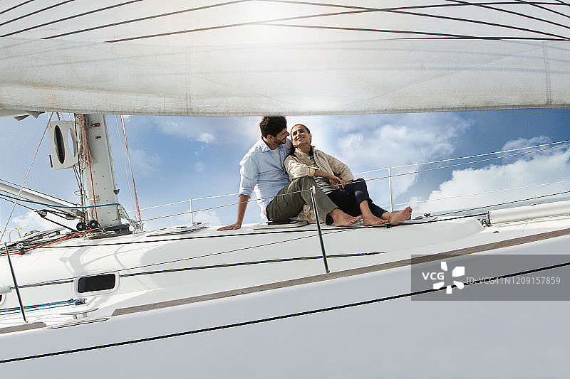 一对夫妇坐在帆船的甲板上，面带微笑。图片素材