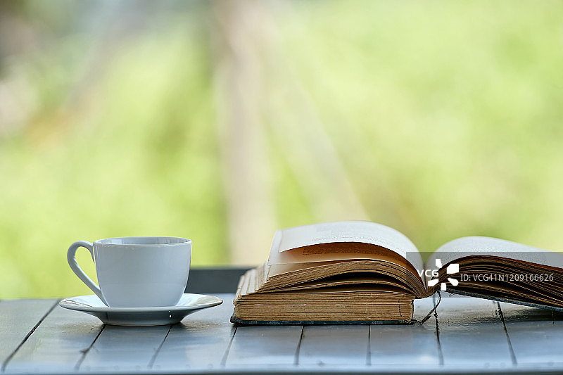 一个白色的咖啡杯和一本书放在一张木桌上图片素材